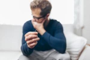 man sitting on couch covering mouth